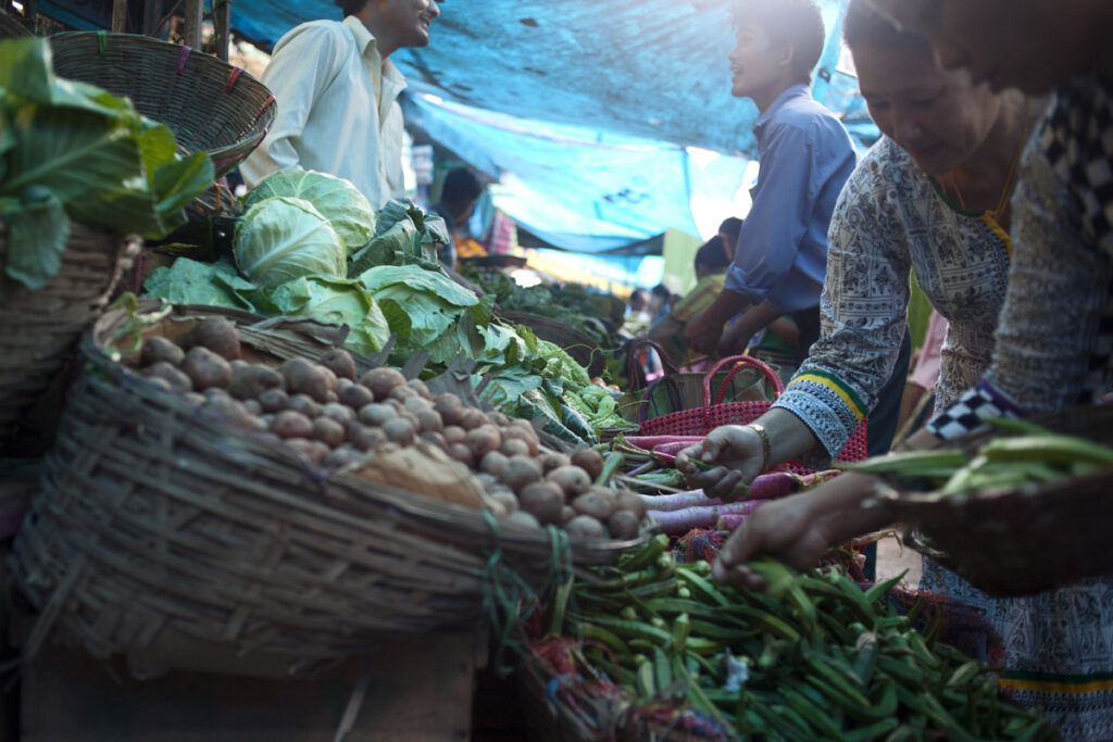 Women picking out organic produce from a shop that sells both organic and non organic produce in Singtham market.